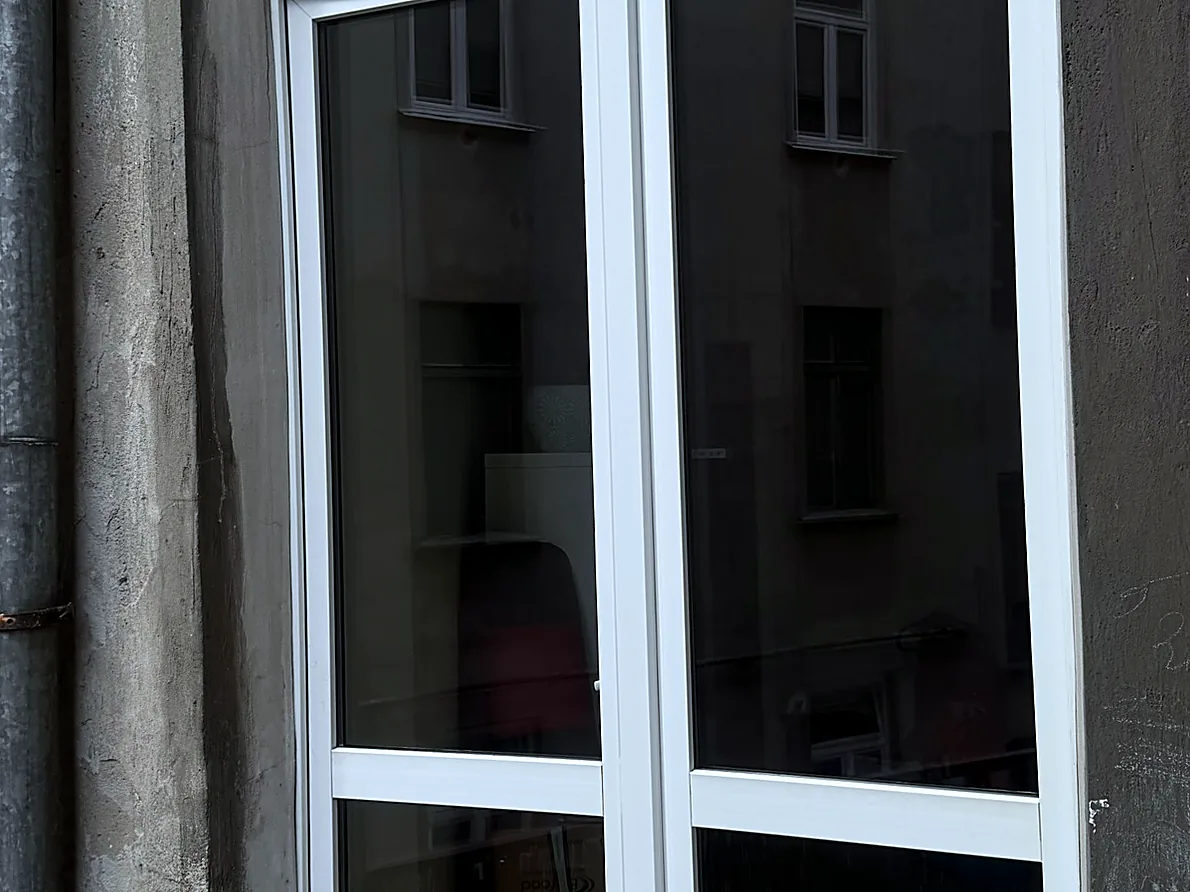 To samo okno po myciu — przejrzysta szyba, ostre odbicie i czyste białe ramy