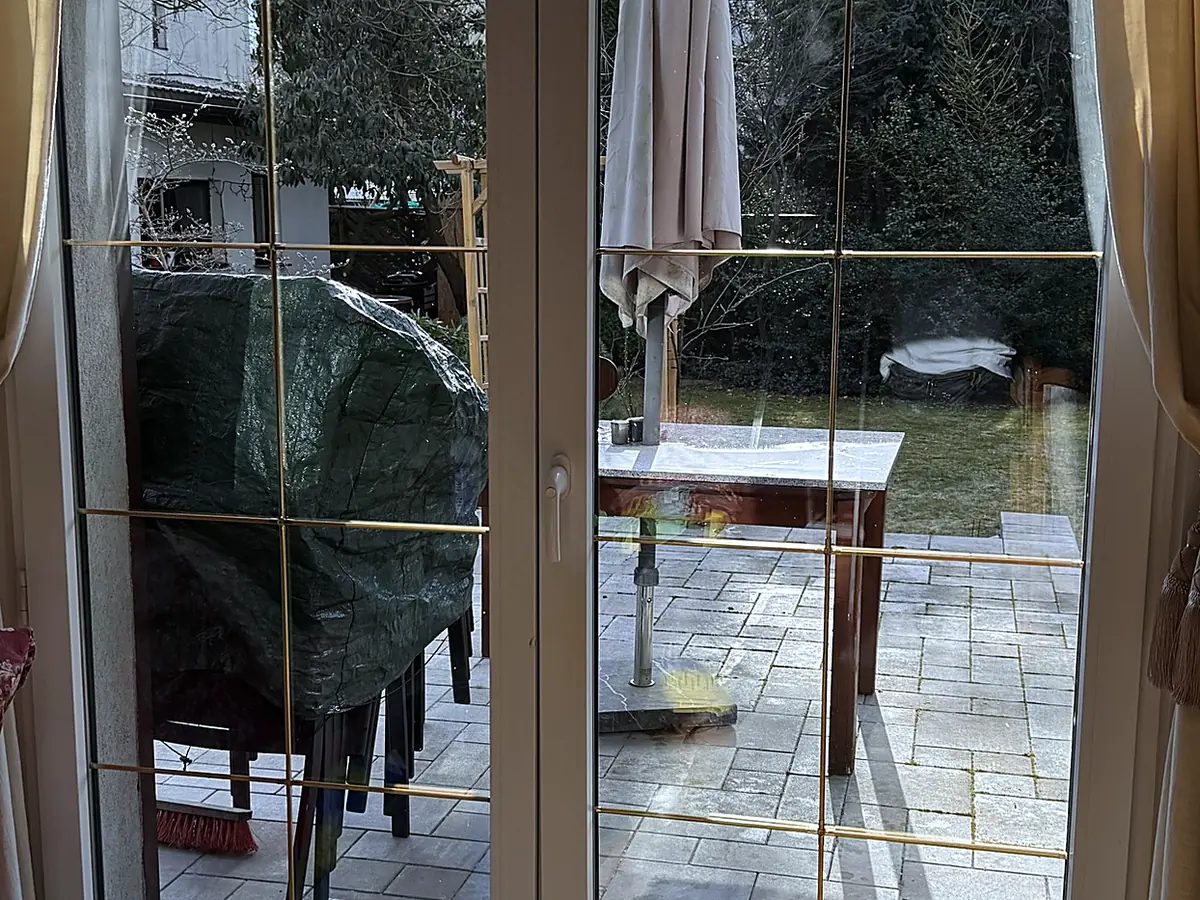 Te same drzwi tarasowe po umyciu — przezroczysta szyba i wyraźny widok na taras i ogród