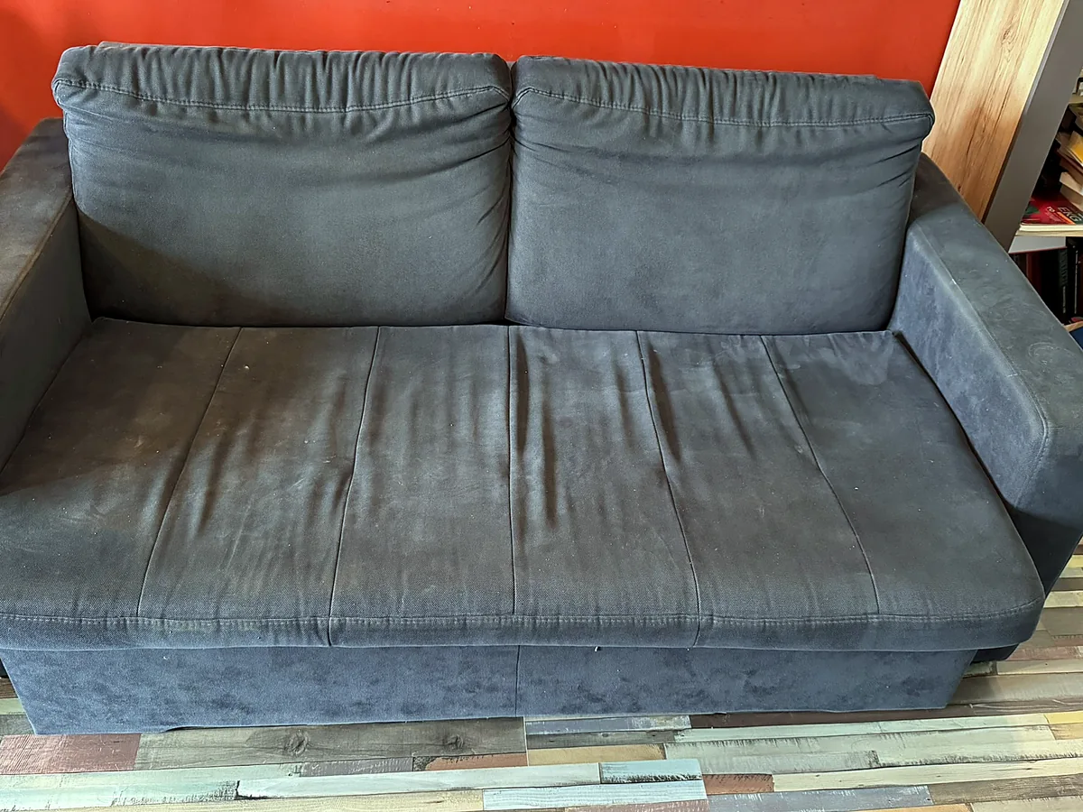 Grafitowa sofa przed praniem — matowa, wytarta tkanina z przetarciami na siedzisku