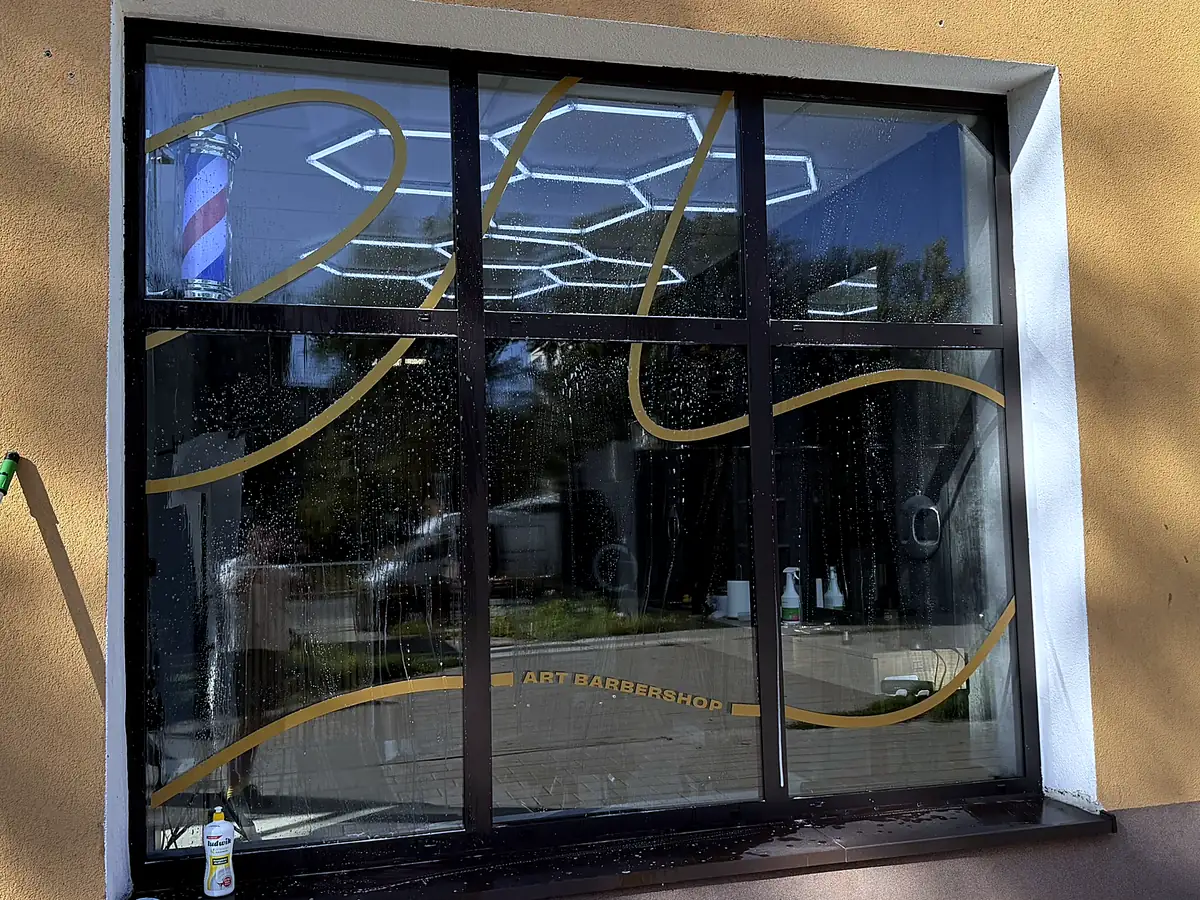 Witryna barbershopu przed myciem — zacieki i zachlapania na szybie, wnętrze lokalu nieczytelne